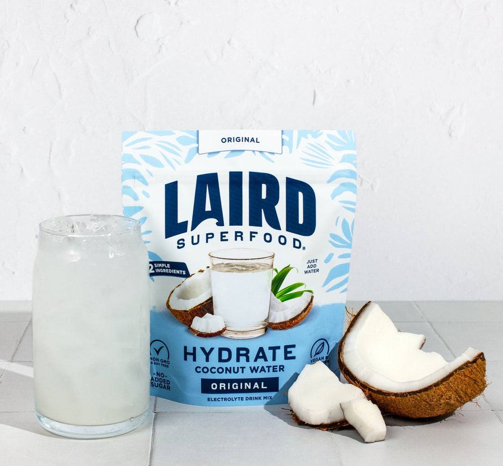 Coconut water in 227g can from Laird Hydrate by Organax Ltd, showing the can's label and fresh coconut imagery.
