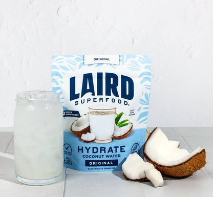 Coconut water in 227g can from Laird Hydrate by Organax Ltd, showing the can's label and fresh coconut imagery.