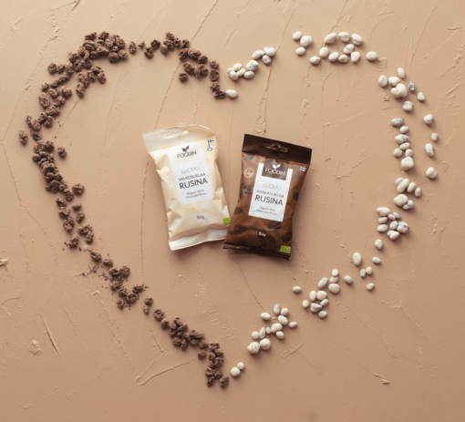 Organic white chocolate raisin snack by Organax Ltd, showing a close-up of the white chocolate-coated raisins in a clear container.
