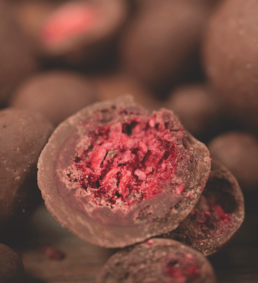 Organic raw chocolate with raspberry from Organax Ltd, showing a 50g package with dark chocolate and fresh raspberry pieces.